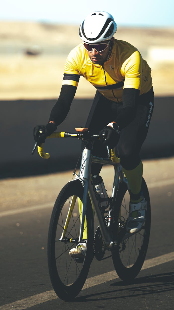 Focused cyclist wearing yellow gear riding a bike outdoors. Captures athleticism and speed.